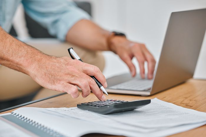 © K Davis/peopleimages.com - Adobe Stock.com Foto: Männerhände auf PC und Taschenrechner