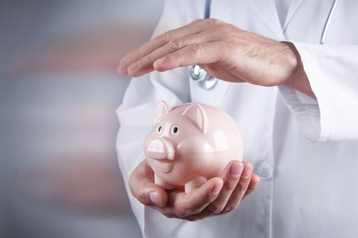 © andranik123 - stock.adobe.com Foto: Arzt hält Hand über Sparschwein